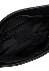 Musta rahakoti sisu, kus on lukk tasku ja nahast silt, millel on vooderduse sees peenelt reljeefne logo.