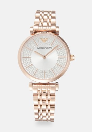 Montre en acier inoxydable rose doré avec un cadran scintillant orné de cristaux, de forme ronde et dotée d'un bracelet à maillons. Présente un logo en haut.