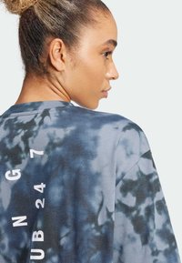 Modra in siva t-shirt z vzorcem tie-dye, sproščenega kroja, okroglim izrezom in belim tiskom "G N G 24 7" na hrbtu.