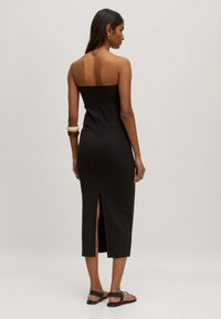 Schwarzes, trägerloses Midi-Kleid mit taillierter Form, seitlichem Schlitz, gerippter Textur und glattem Stoff. Hat freiliegende Schultern und ein schlichtes Design.