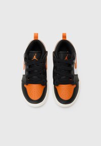 Sneakers neri e arancioni con upper in pelle e tessuto, punta perforata, lacci neri e suola in gomma bianca. Un accento arancione sul tallone.