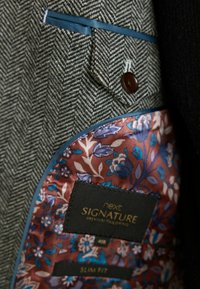 Tissu en chevrons gris avec une poche bordée de bleu, présentant une doublure satinée florale dans des teintes de bourgogne, bleu et crème. Comprend une étiquette indiquant la taille.