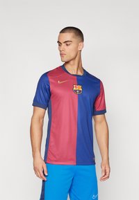 Maglia replica del FC Barcelona con metà marrone e blu, logo Nike in oro, maniche corte e tessuto testurizzato.