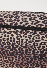 Borsa con stampa leopardata caratterizzata da una superficie in tessuto liscio, zip nera e sfondo beige con macchie marroni scure di diverse dimensioni.