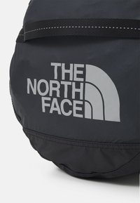 Svart ryggsäck från North Face med grå logotyp, som har en rund form, hållbart tyg och svarta webbdetaljer längs toppen.