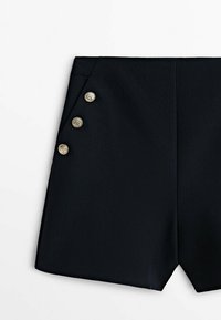 Short noir cintré avec une taille haute et trois boutons décoratifs dorés sur un côté sur fond blanc.