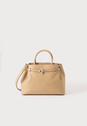 Beige læderhåndtaske med dobbelte håndtag, frontbælte med sølvspænde og justerbar skulderrem på hvid baggrund.