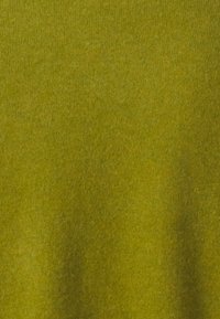 Tejido de punto verde que muestra una textura suave, color uniforme y variaciones sutiles, indicativo de un material de mezcla de lana o algodón.