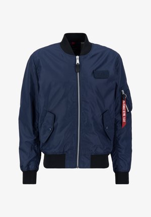 Námořnická modrá bomber bunda s předním zipem, žebrovanými manžetami a lemem, obsahující boční kapsy a červenou nášivku na rukávu. Hladká textura.
