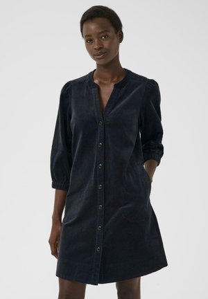 Navy corduroy shirt dress with a V-neck, long puff sleeves, and button front. Features side pockets and a relaxed fit.