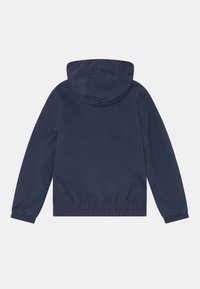 Marineblauwe lichtgewicht jas met een capuchon, elastische manchetten en een geplooide zoom. Glad textuur, eenvoudig ontwerp zonder extra accenten.