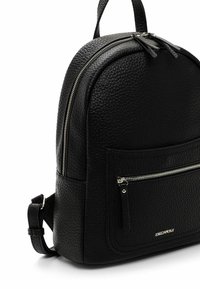 Zaino in pelle nera con texture, forma arrotondata, doppia cerniera, tasca frontale con zip e logo in basso. Spallacci regolabili.