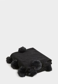 Plaid nera realizzata in morbido tessuto, con accenti di pompon soffici lungo i bordi. La coperta è piegata ordinatamente.