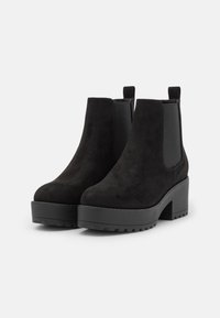 Svarta mocka ankelstövlar med en chunky plattform och blockklack, med elastiska sidopaneler och dragflikar för lätt av- och påtagning.