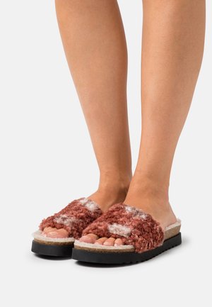 Brown and white fuzzy slide sandals with a textured upper and cork footbed. Thick black sole provides contrast and stability. Open-toe design.