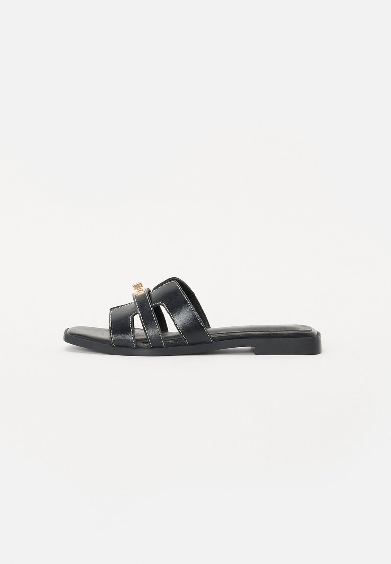 Sorte skinnsandaler med flere remdesign, flat såle, subtil sømdetalj og en liten metallkledning.
