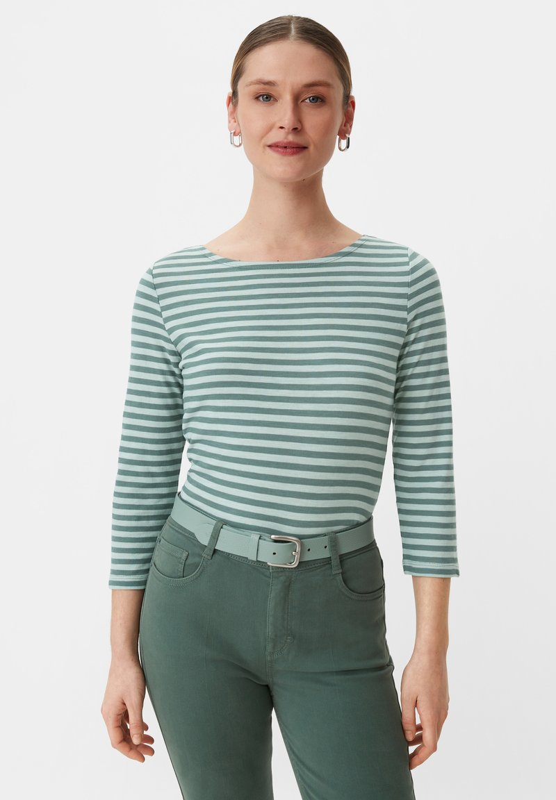 Grün gestreifte Langarmbluse mit Bootsausschnitt, kombiniert mit einem grünen Gürtel und Hose, die eine glatte Textur und eine figurbetonte Passform aufweisen.