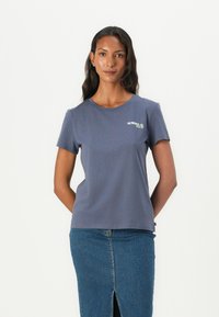 Kortsleeve marinblå t-skjorte i mykt stoff, med en liten "SUMMER CLUB" grafikk i grønt. Kombinert med et denim skjørt.