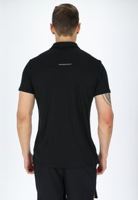 Svart kortärmad polo-shirt i lättviktigt material. Har en rak nederkant och en liten logotyp på övre ryggen. Tätsittande design.