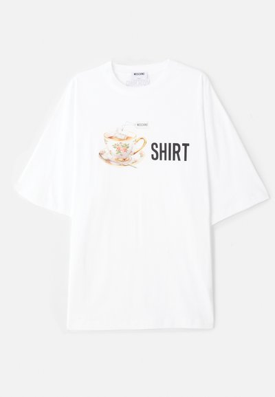 Balts pārāk liels T-krekls ar krāsainu tējas krūzes grafiku, kurai ir ziedu detaļas un vārds "KREKLS" treknām melnām burtiem zem tā.