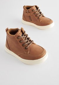 Bruine leren halfhoge schoenen met een gestructureerde afwerking, ronde neus en contrasterende witte rubberen zool. Voorzien van bruine veters en een ritssluiting aan de zijkant.