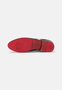 Suola di scarpa formale in pelle nera, con fondo rosso brillante. Logo inciso e dettagli delle taglie sono visibili. Texture liscia, forma arrotondata.
