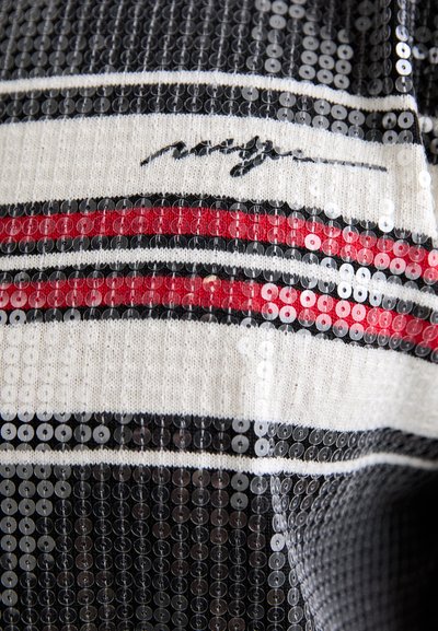 Haut à sequins avec des rayures horizontales en noir, rouge et blanc ; présente une texture en tricot et un logo en cursive sur le tissu.