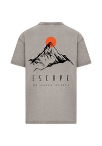 Gray cotton T-shirt featuring a mountain graphic, an orange sun, and text saying "ESCAPE AND DISCOVER THE WORLD" at the bottom.