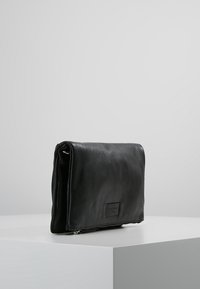 Černá kožená psaníčko s obdélníkovým tvarem, vybavené zipovým uzávěrem a texturovaným povrchem. Žádné viditelné kování ani vzory.