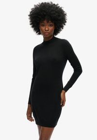 Schwarzes Strickkleid mit hohem Ausschnitt, langen Ärmeln und tailliertem Schnitt. Die glatte Textur und die gerippten Bündchen betonen das Design.