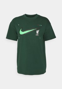 Zielona bawełniana koszulka z dużym czarnym logo Nike oraz logo Liverpool FC. Udekorowana gwiazdkami i kolorowymi kropkami. Krótkie rękawy.