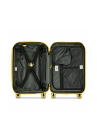 Maleta amarilla rígida abierta con interior negro, correas cruzadas ajustables a la izquierda y compartimentos de malla con cremallera en el lado derecho.