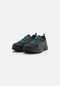 Baskets de sport noires avec des lacets turquoise, des accents orange, des semelles texturées et une adhérence en caoutchouc. Conçues pour le confort et la stabilité.