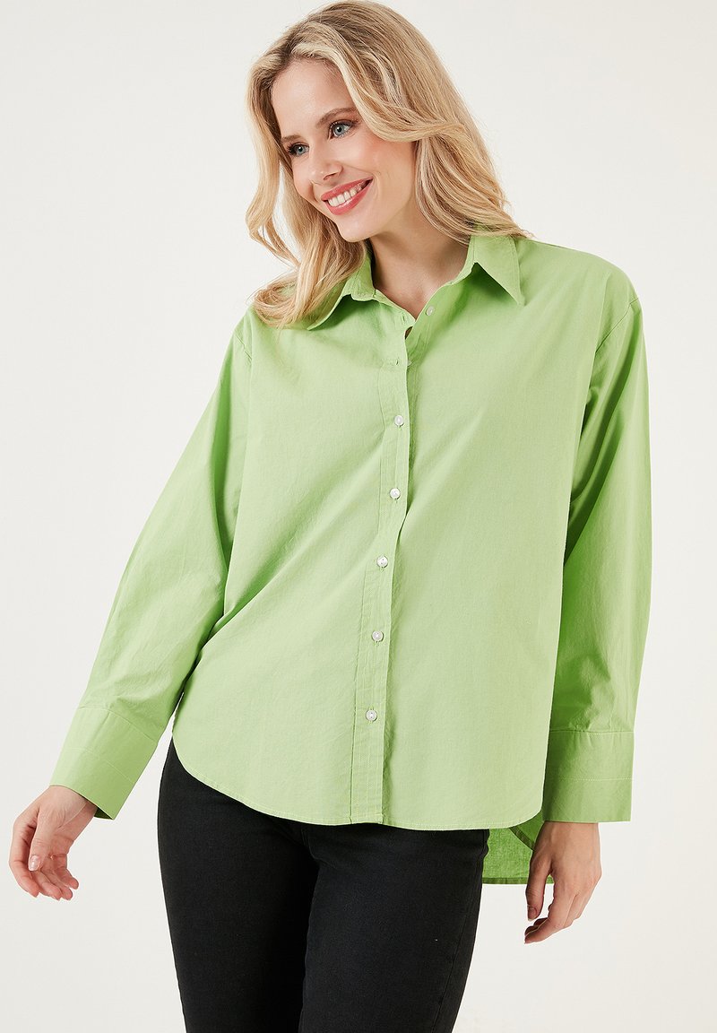 Camicia button-up verde chiaro con colletto a punta, maniche lunghe, orlo arrotondato e una texture di cotone liscia. Presenta piccoli bottoni bianchi.