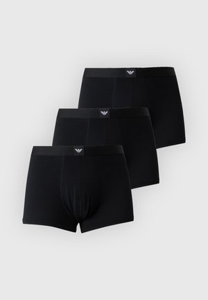 Τρία μαύρα ανδρικά boxer briefs με επώνυμα λάστιχα στην μέση, στοιβαγμένα με ελαφρά μετατόπιση πάνω σε απλό ανοιχτό φόντο.