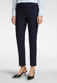 Pantaloni su misura blu navy con vestibilità slim, dotati di tasche, una texture liscia e abbinati a décolleté nere con punta a stiletto.