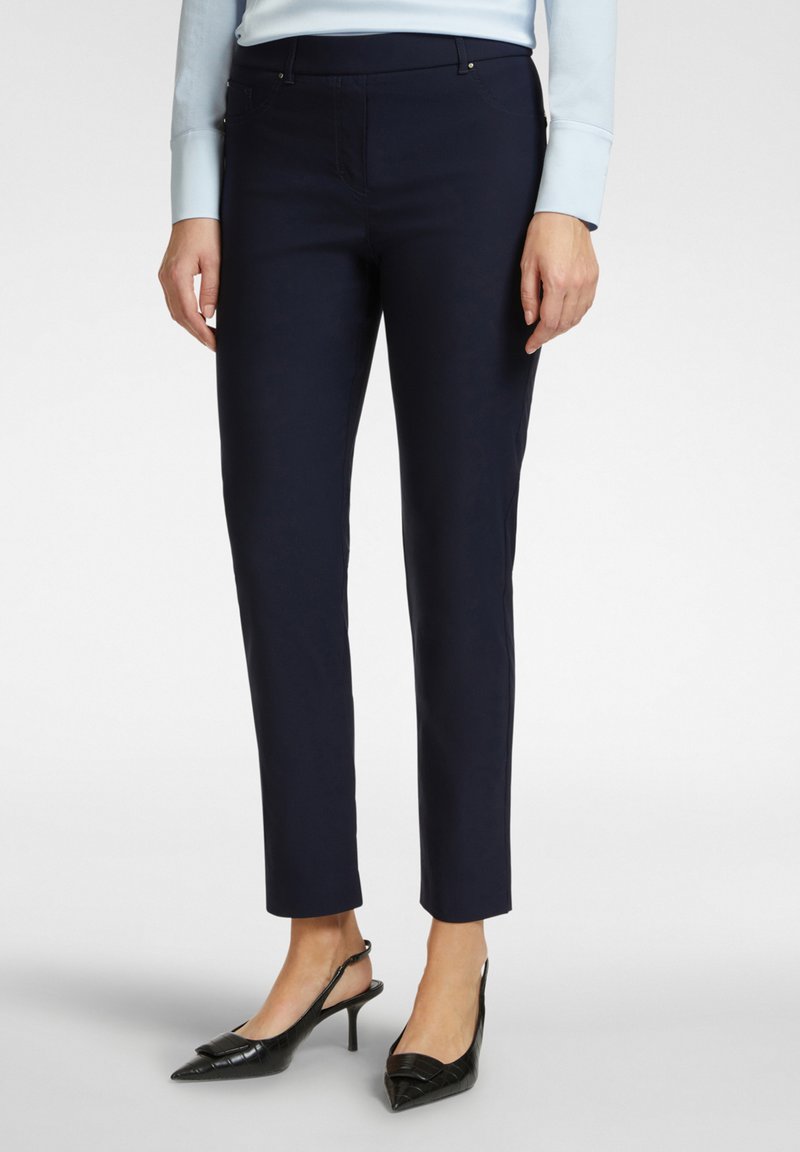 Pantaloni su misura blu navy con vestibilità slim, dotati di tasche, una texture liscia e abbinati a décolleté nere con punta a stiletto.