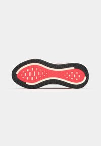 Semelle de chaussure mettant en avant un design ondulé avec du caoutchouc noir, une section centrale rouge vif, une adhérence texturée et des accents blancs le long des bords.