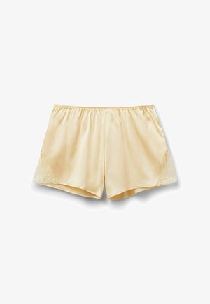 Pantalones cortos de satén color crema con cintura elástica y detalles de encaje en los laterales, extendidos sobre un fondo blanco.