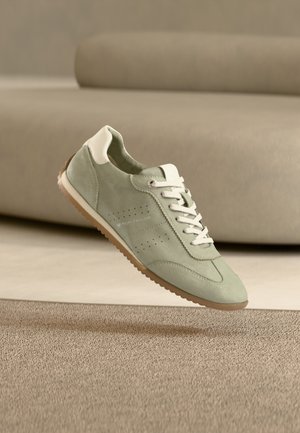 Ανοιχτό πράσινο σουέντ αθλητικό παπούτσι με λευκές λεπτομέρειες, σχεδίαση με κορδόνια, διάτρητα στοιχεία στις πλευρές και υφή καουτσούκ στη σόλα.