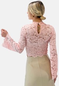 Rosa Spitzen-Crop-Top mit ausgestellten Ärmeln und einem Schlüsselaugen-Detail im Rücken, verziert mit floralem Muster und gewellten Kanten.