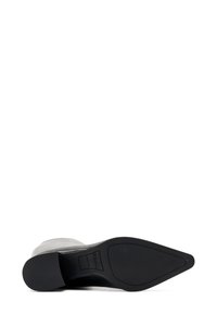 Bottines en cuir noires à bout pointu vues du dessous, montrant la semelle texturée et la marque "FRAU Made in Italy".