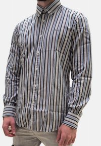 Camicia a maniche lunghe con bottoni, a righe verticali bianche, marroni, blu e grigie. Presenta un colletto e chiusura con bottoni. Tessuto testurizzato.