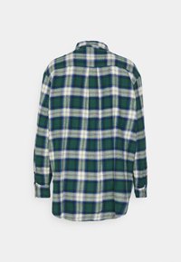 Chemise à manches longues à carreaux verts, blancs et bleus vue de dos, avec col et poignets boutonnés sur fond blanc.