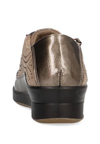Zapatillas de bronce y beige con un acabado texturizado, que cuentan con acentos perforados y una suela de goma negra. Diseño estructurado con soporte acolchado.