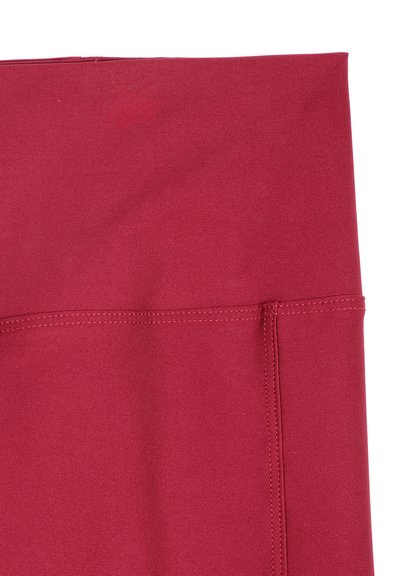 Gros plan sur un tissu rouge avec des coutures cousues, probablement une partie d'un vêtement ou d'un produit textile.