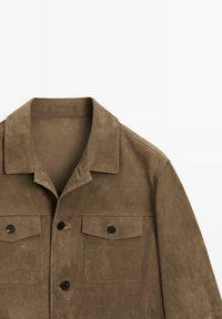Bruine suède jas met een puntige kraag, twee met knopen afsluitbare borstzakken en zwarte knopen aan de voorkant op een witte achtergrond.