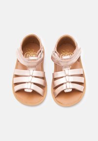 Παιδικά μεταλλικά σανδάλια σε ροζ χρυσό χρώμα, με τρεις λουριά μπροστά και έναν λου ρί γύρω από τον αστράγαλο, πάνω σε ανοιχτό φόντο.