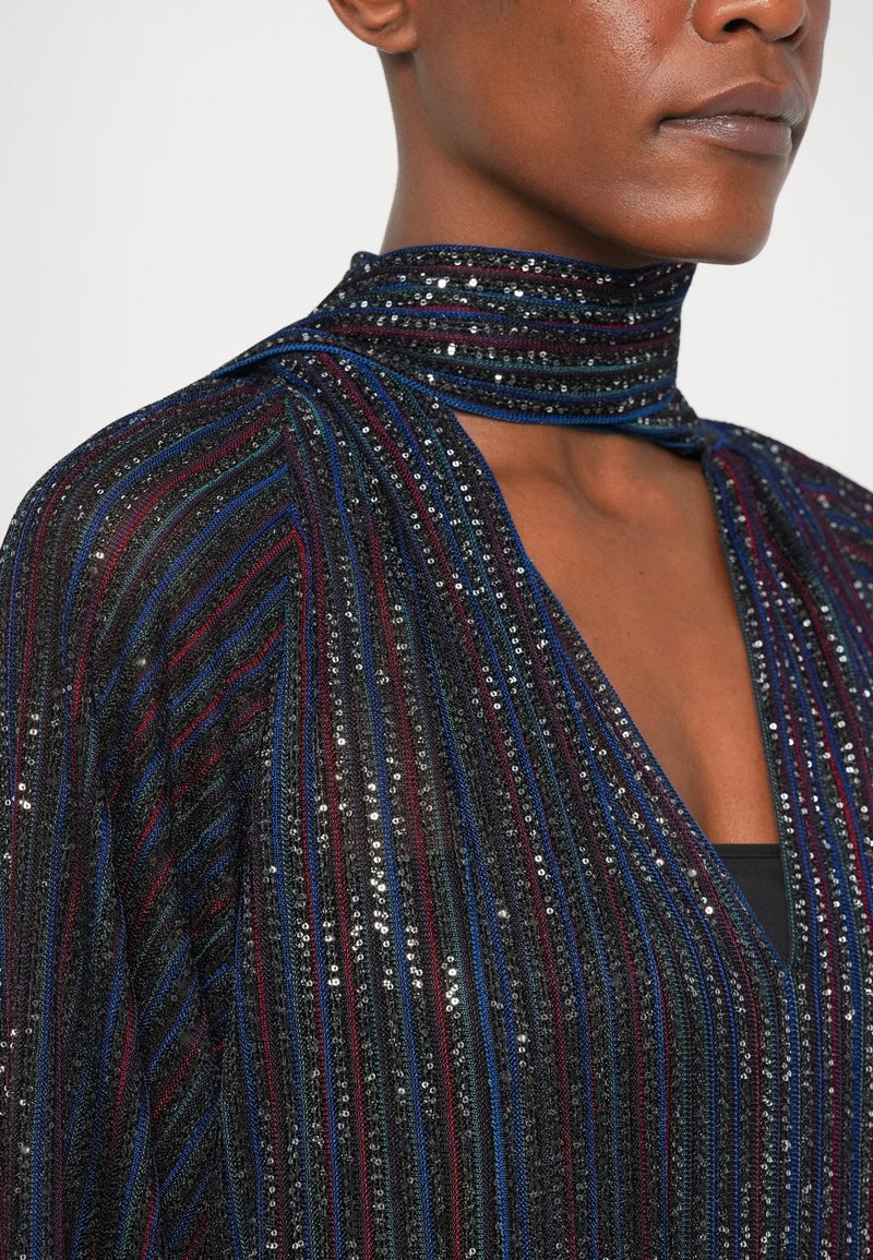 Black fabric top with shimmering vertical stripes in red, blue, and silver sequins. Features a high neck and V-shaped neckline.