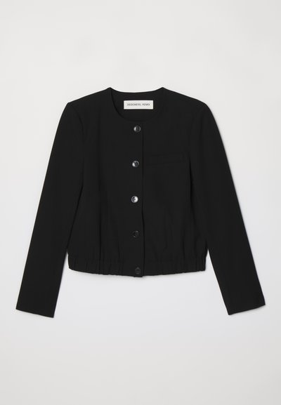 Black cropped jacket made from smooth fabric, featuring a round neckline, front button closure, and a single chest pocket. Elasticated hem.